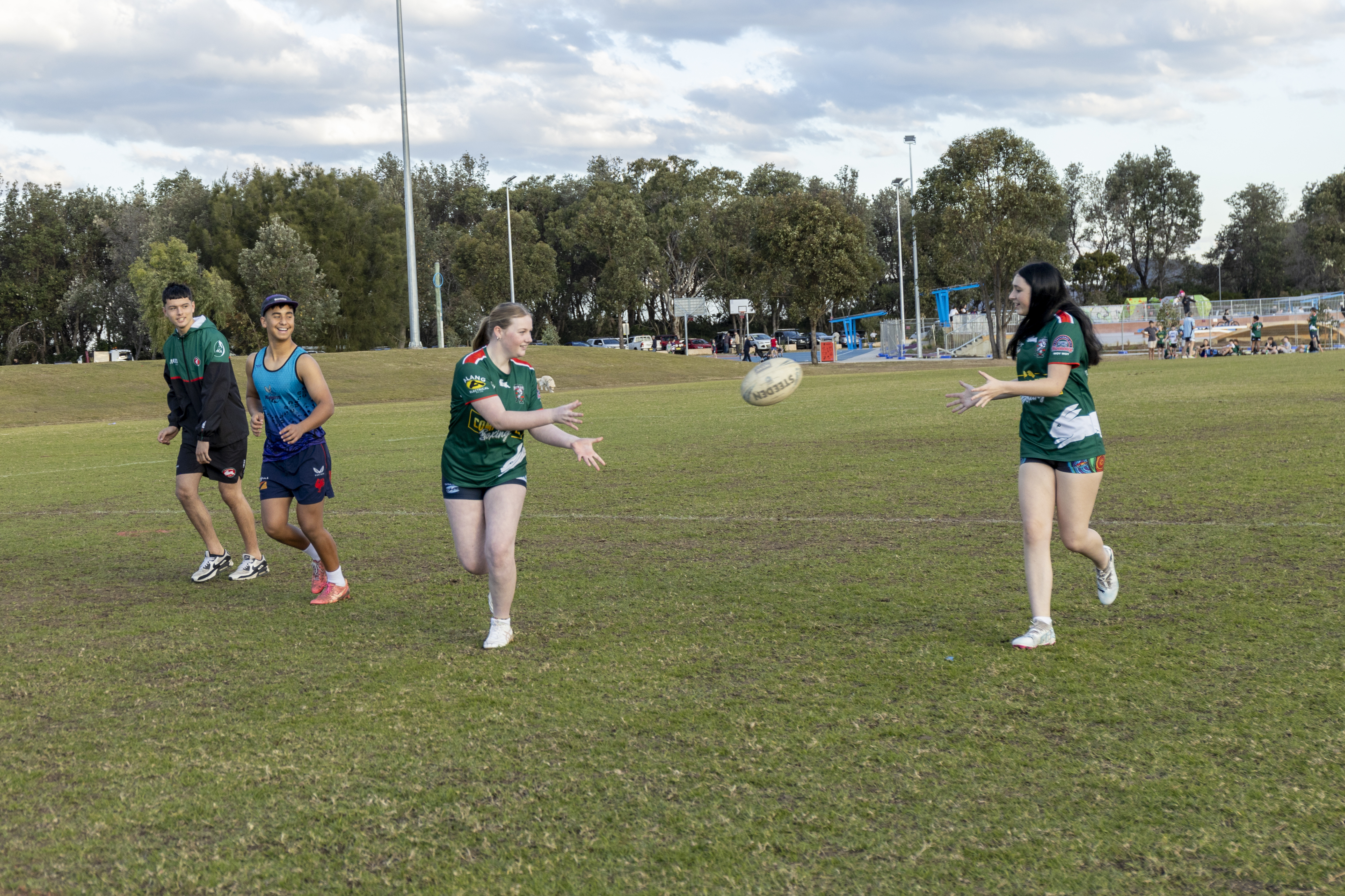 girls passing rugby ball with boys alongside